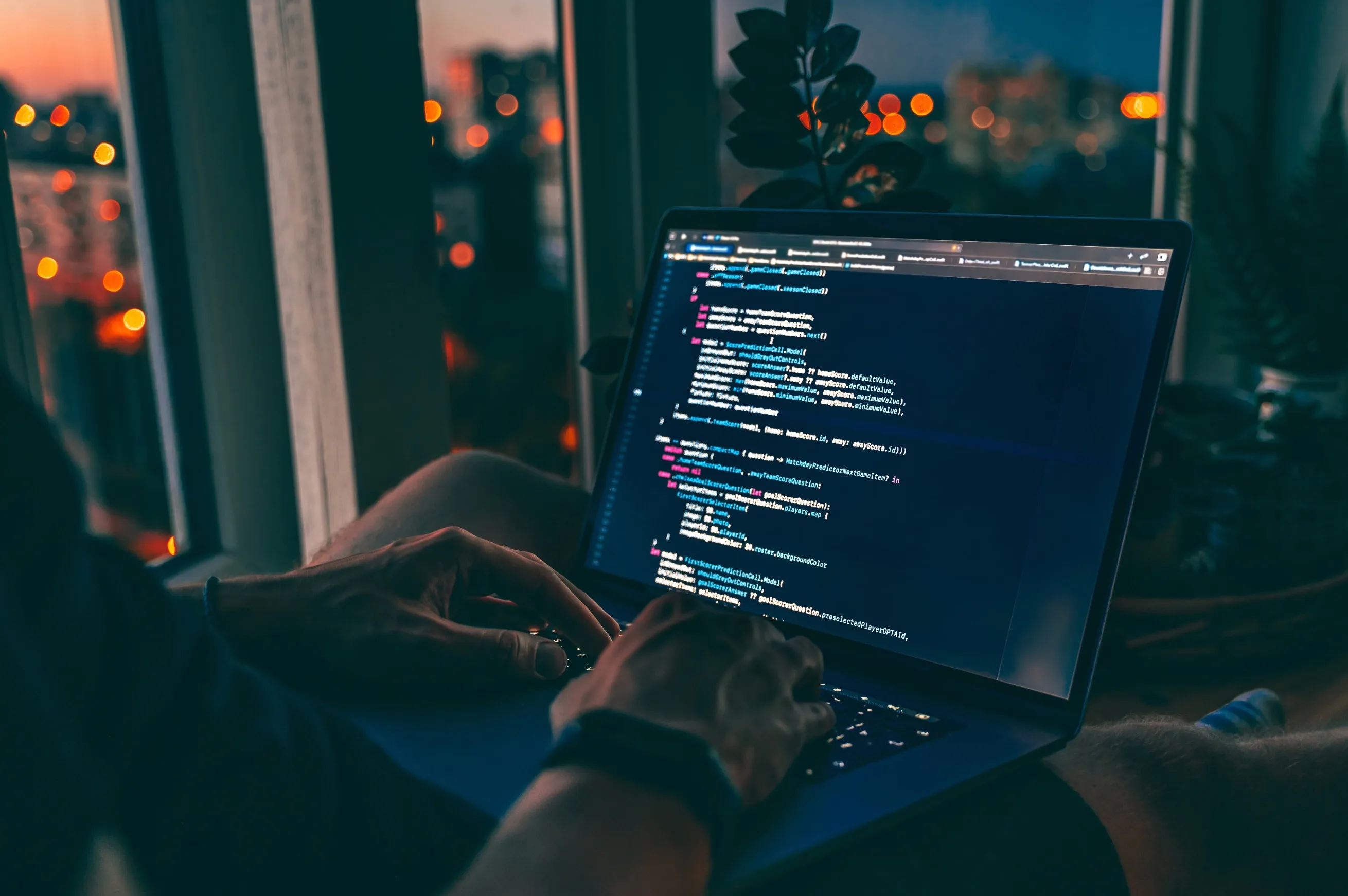 Personne travaillant le soir sur un ordinateur portable affichant du code