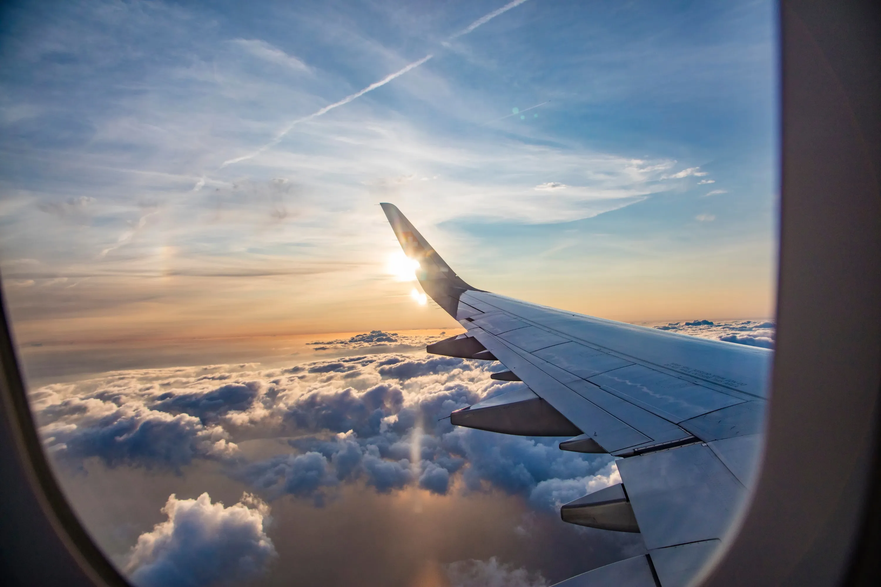 Aile d’avion et mer de nuages vues depuis un hublot au coucher du soleil